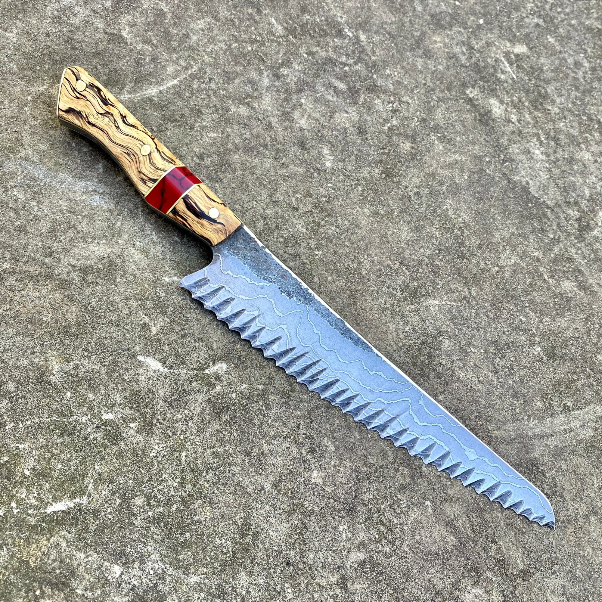 Knife with a textured handle and a serrated blade on a gray surface.