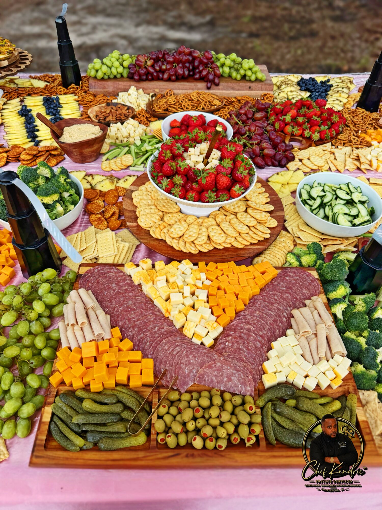 A large spread of various cheeses, meats, fruits, and vegetables arranged on a table for a feast.