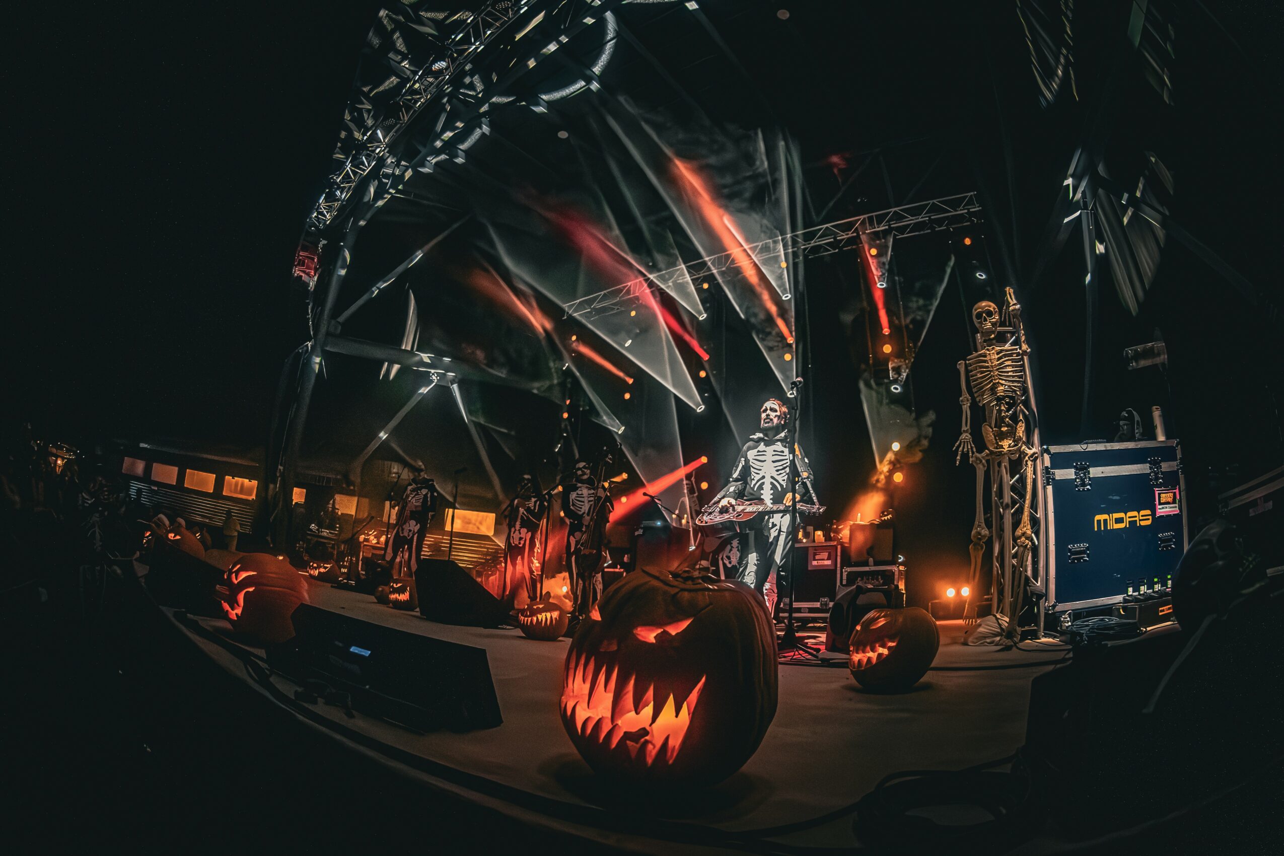 Stage with Halloween decorations, including a carved pumpkin with a glowing face, and bright stage lights at night.