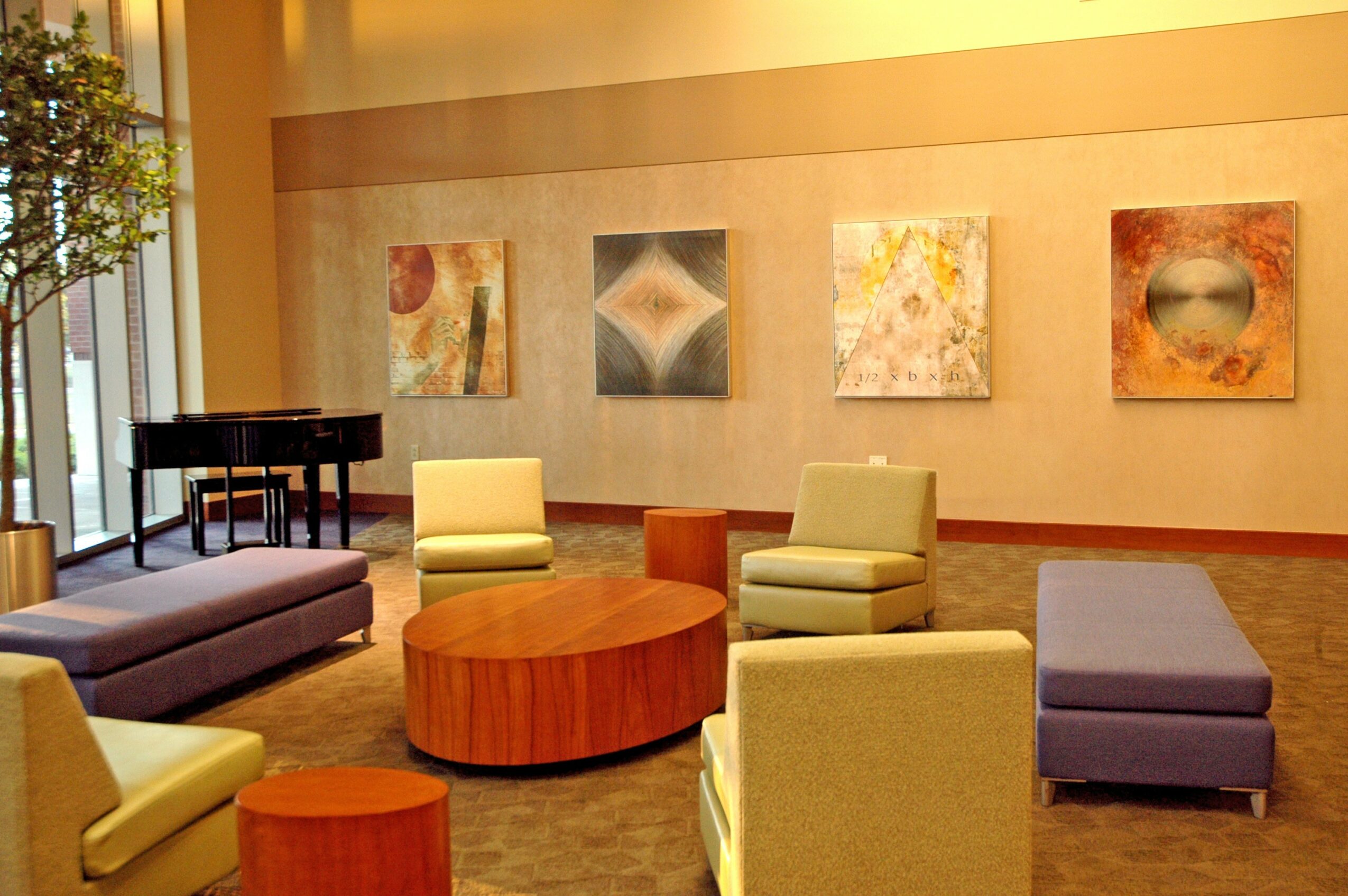 Interior room with chairs, a sofa, a piano, and abstract artwork on the wall.