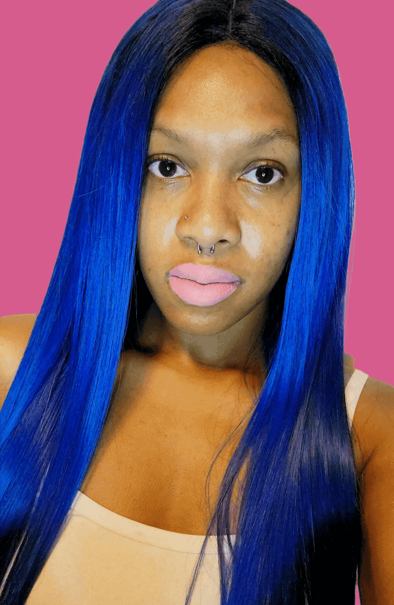 Portrait of a woman with long, straight blue hair and pink lipstick, against a pink background.