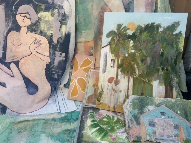 Various artworks including a painting of a woman, a landscape with trees, and a house, displayed on a surface.