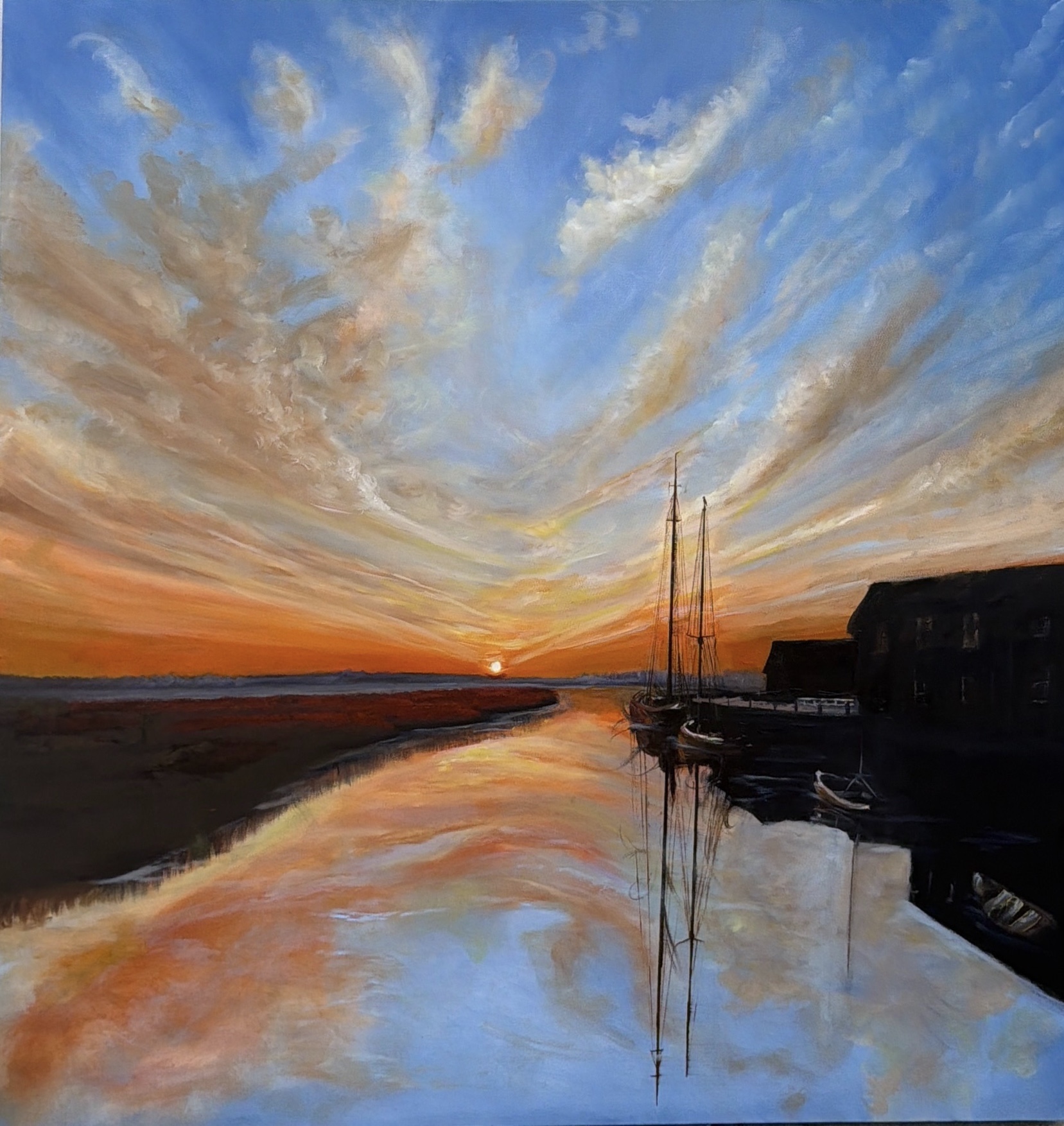 Sunset over water with sky filled with clouds, sailboat, and buildings reflected in the water.