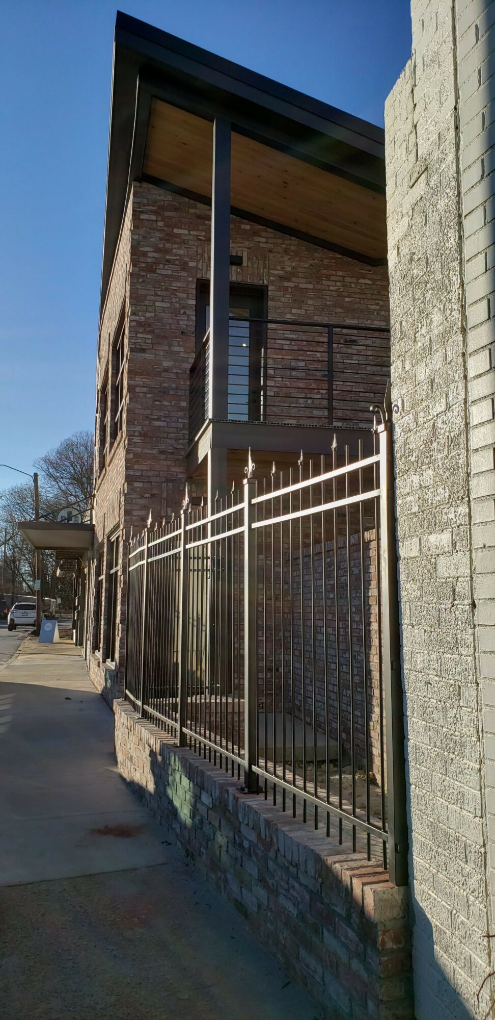 View of a balcony with metal railing, brick wall, and a wooden ceiling, seen from below.