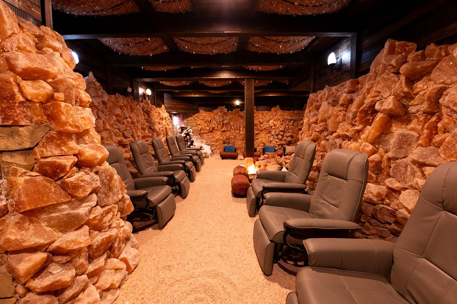 Seating area with chairs between rocky walls in a dimly lit underground space.