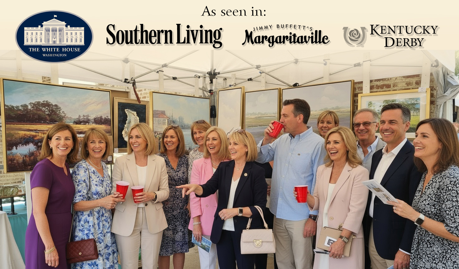 Group of people at an outdoor event under a tent, holding drinks and talking, with artwork displayed behind them.