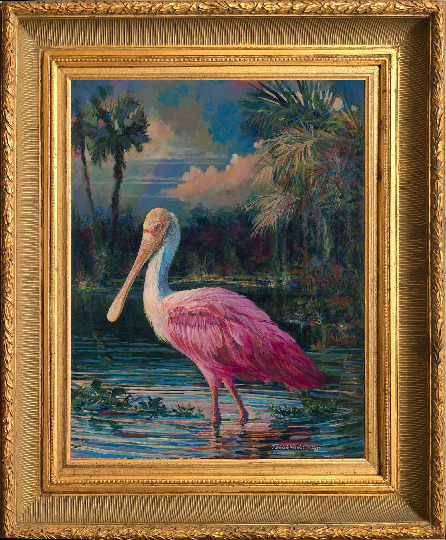 A pink flamingo standing in water with trees and a cloudy sky in the background.