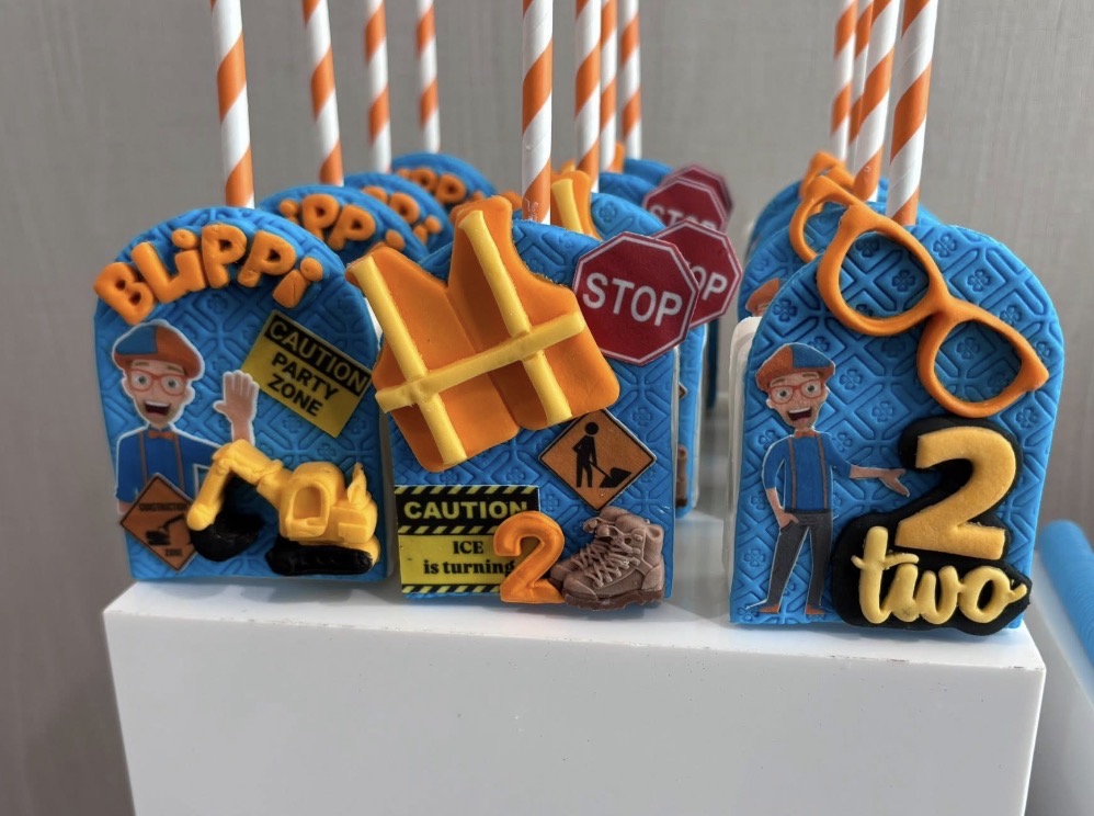 Party decorations with blue, orange, and yellow themed items, including sunglasses, traffic signs, and a toy hammer, on a white surface.