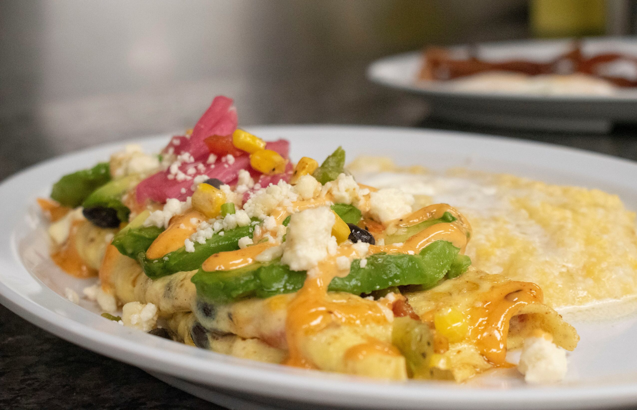 Plate with nachos topped with jalapenos, cheese, and pickled vegetables, alongside a side of melted cheese or sauce.