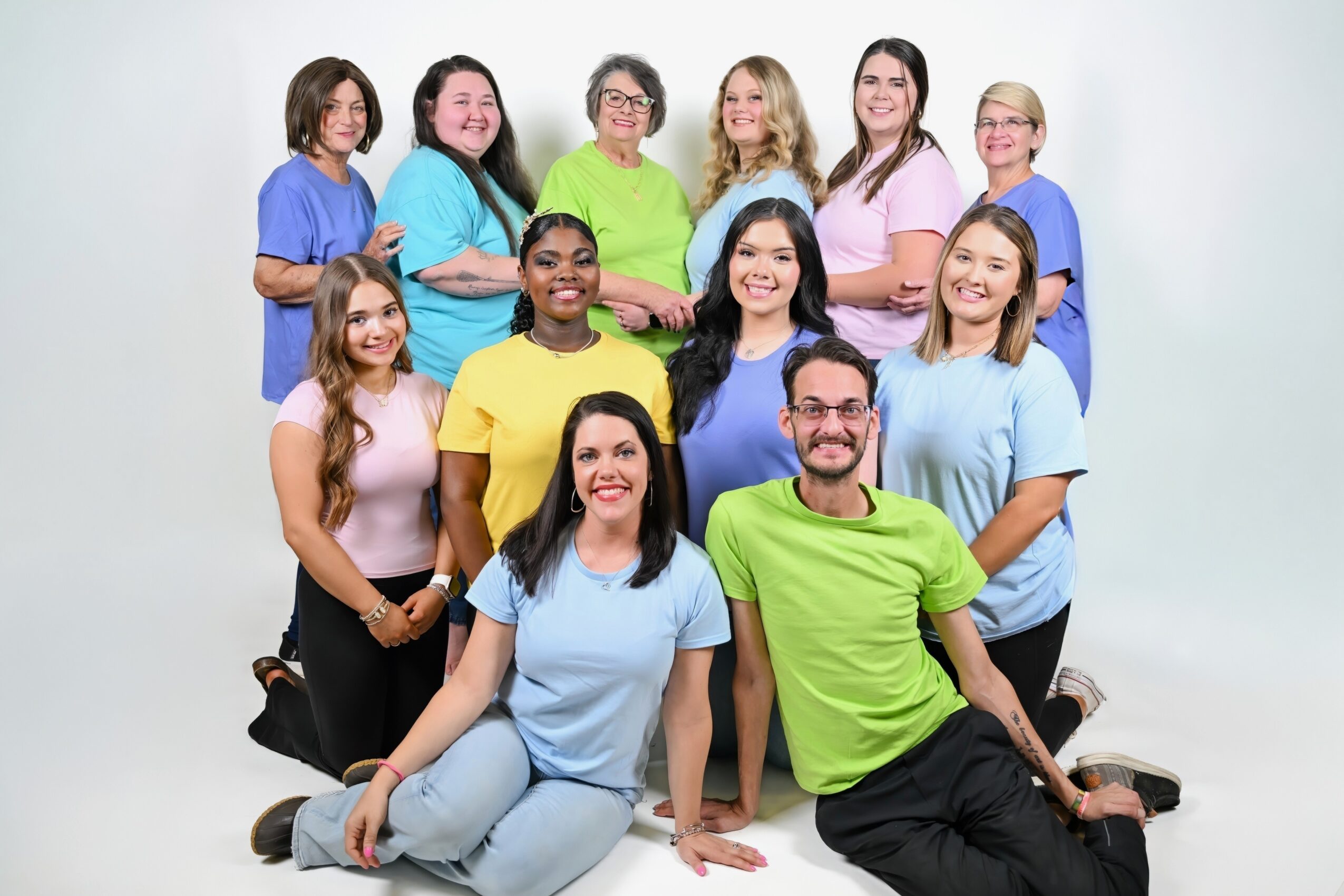 A group of ten people pose together in three rows against a plain light background.