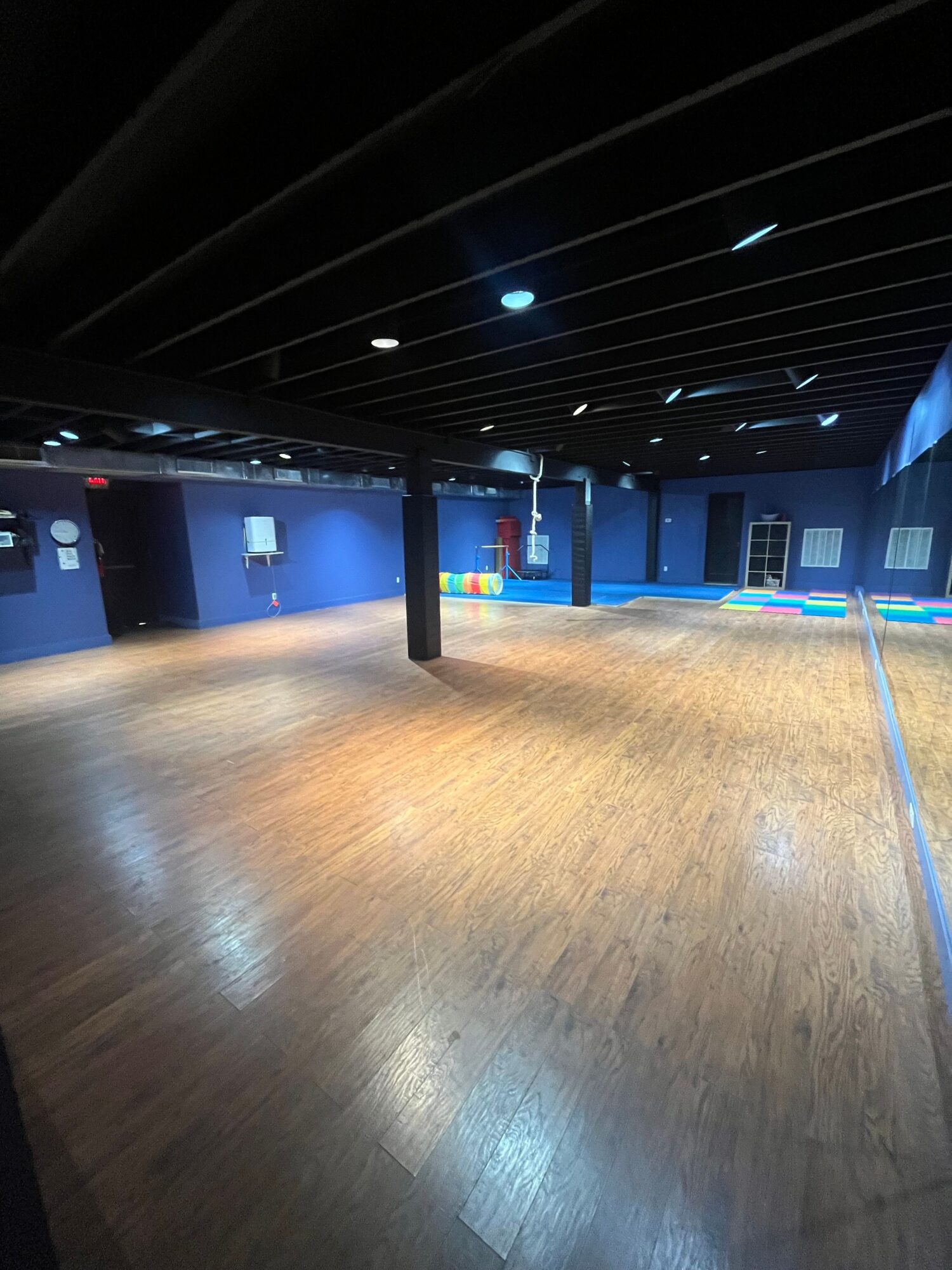 A wooden floor beside a dark ceiling and blue-lit walls in an indoor space.
