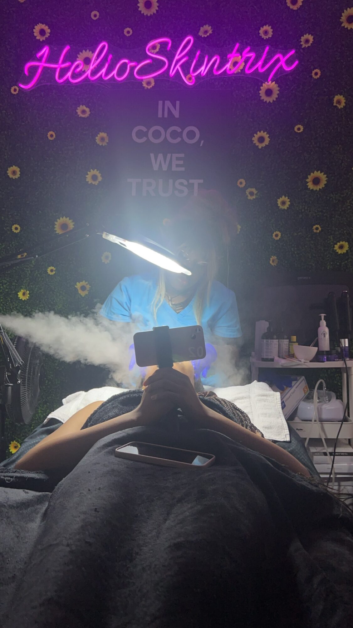 Person receiving a facial treatment in a spa with a sign reading 'Hello Skin' in the background.