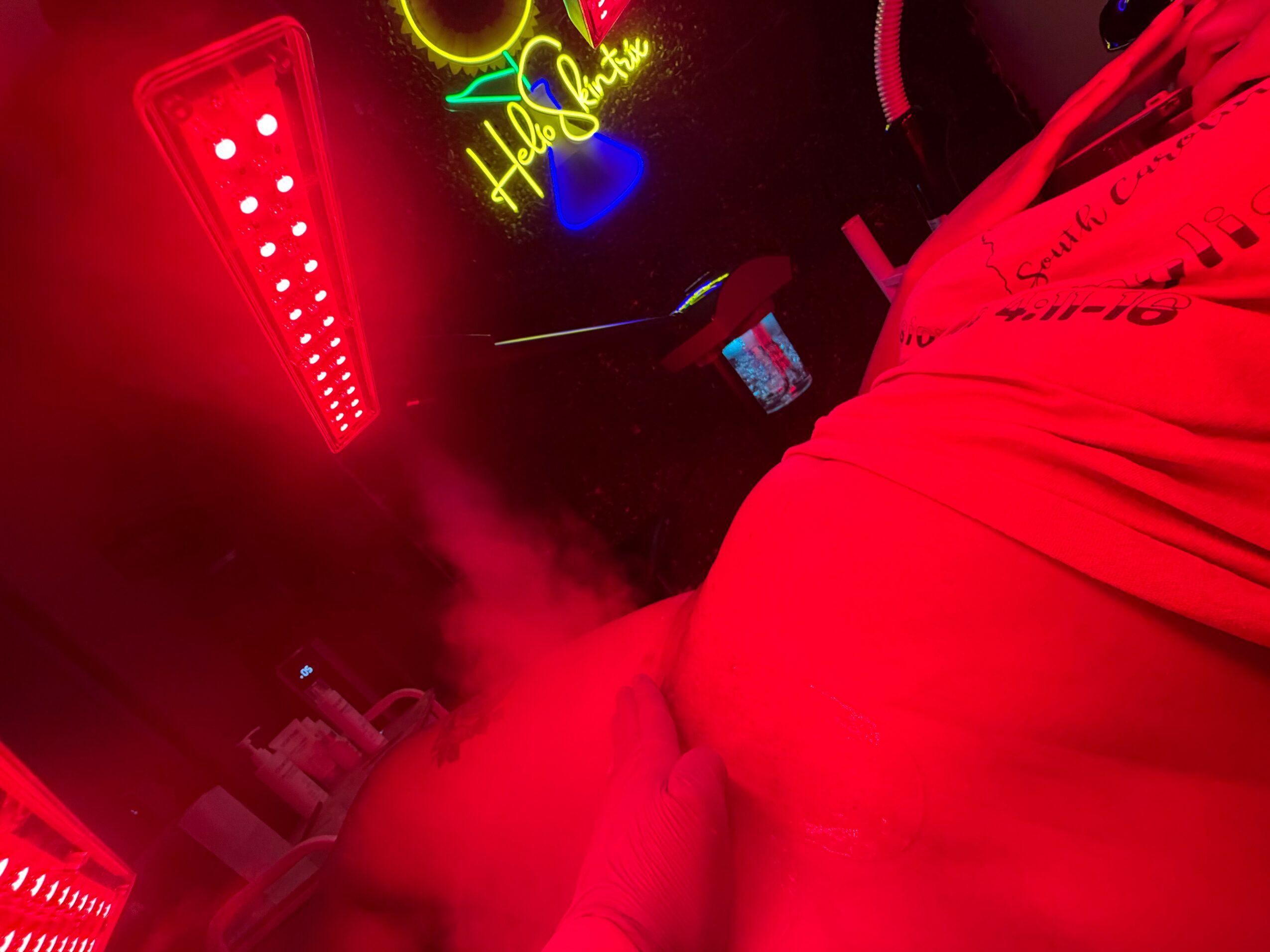 Neon signs and red lighting in a room, with part of a person wearing a red shirt visible.