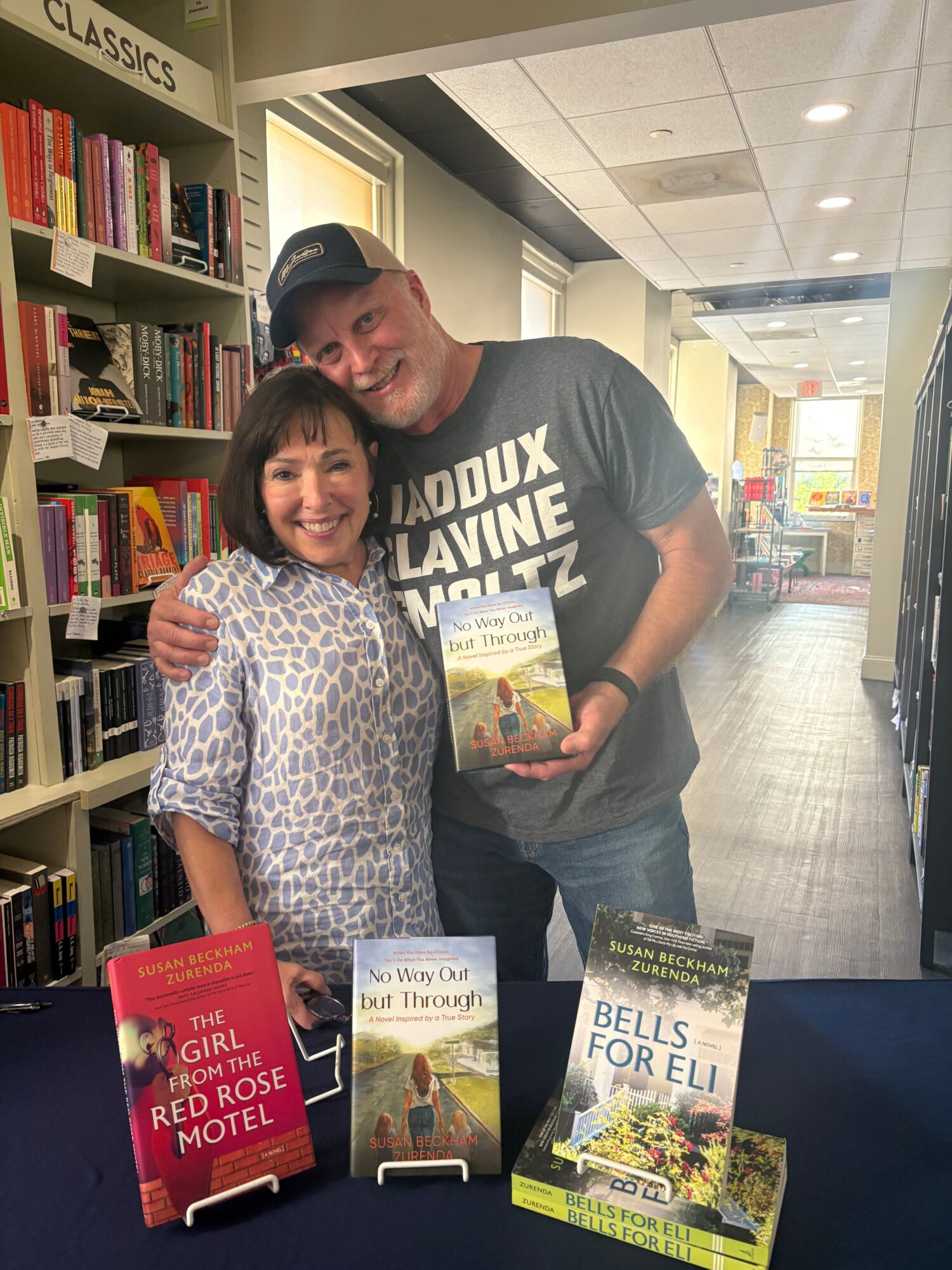 Two people stand in a bookstore holding books, with shelves and displays around them.