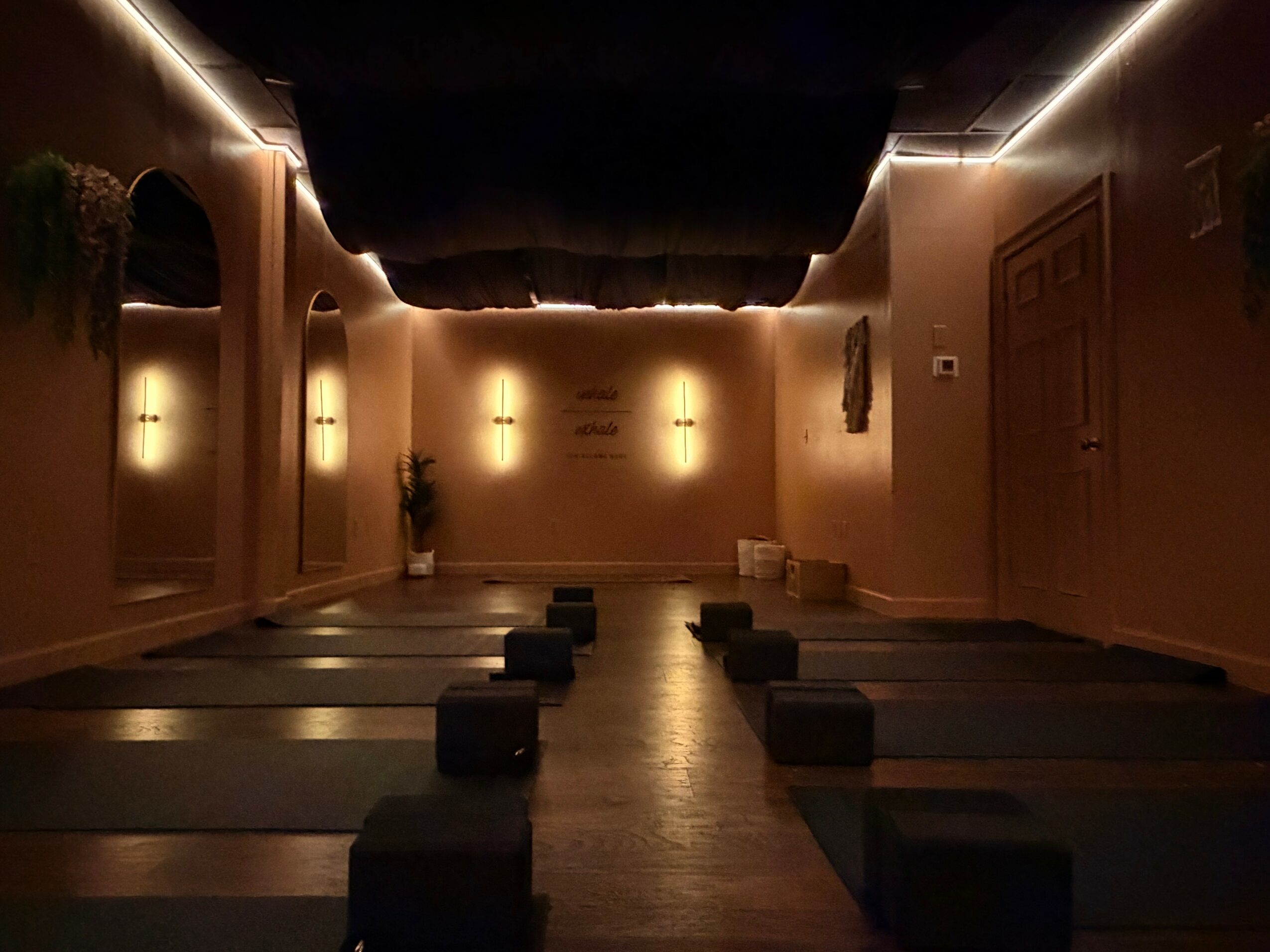 Yoga mats and blocks arranged in a dimly lit room with soft lighting and wall decorations.