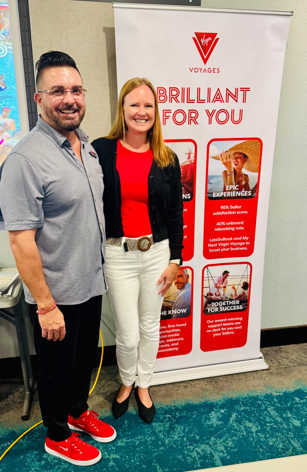 Two people stand beside a promotional banner reading “Brilliant for You” in an indoor hallway.
